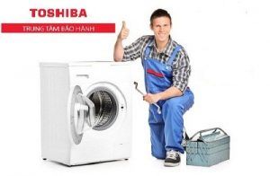 A repairman holding a spanner and giving thumb up next to a washing machine isolated on white background